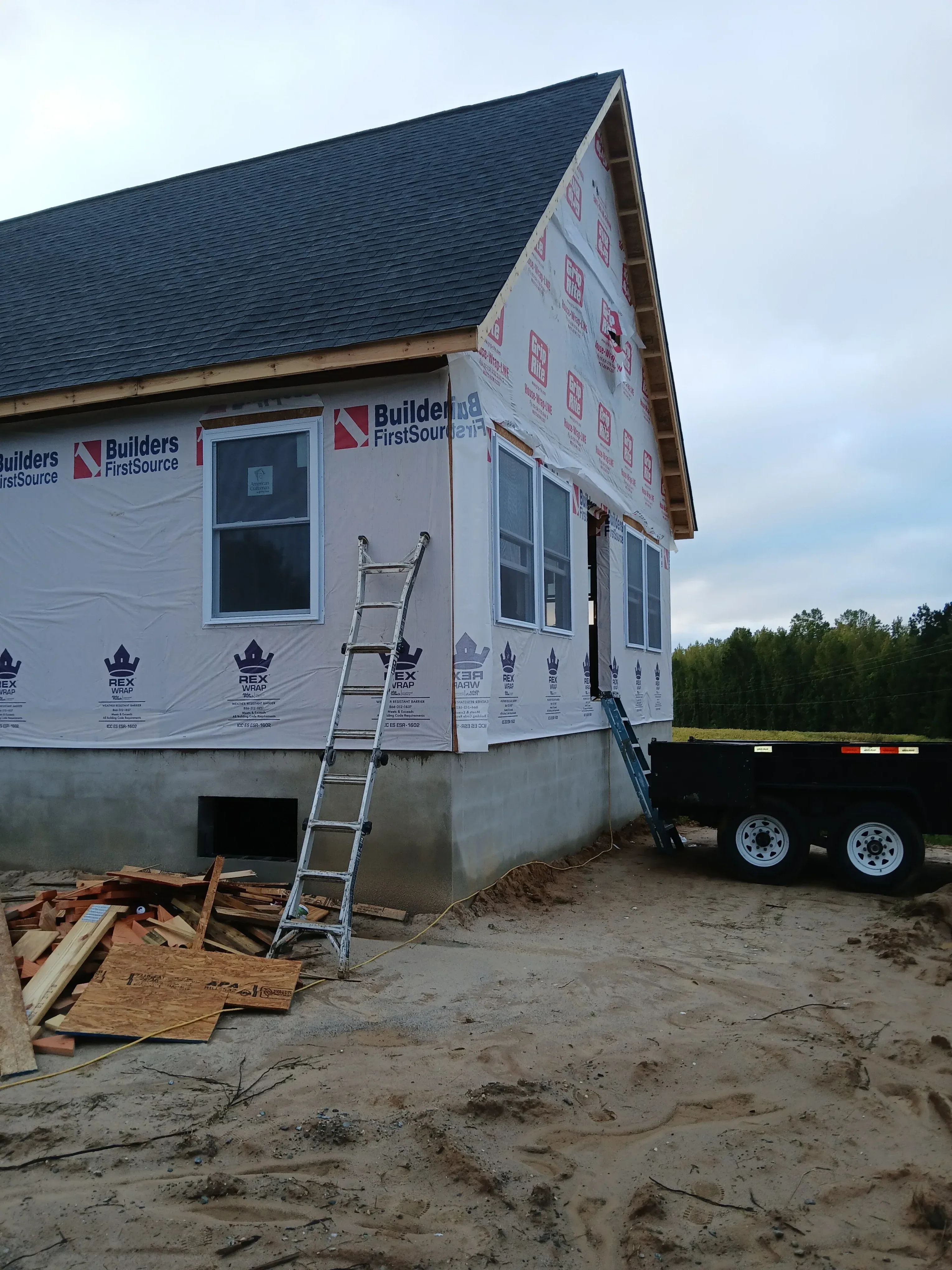Residential framing with metal roof, house wrap, and window openings under construction