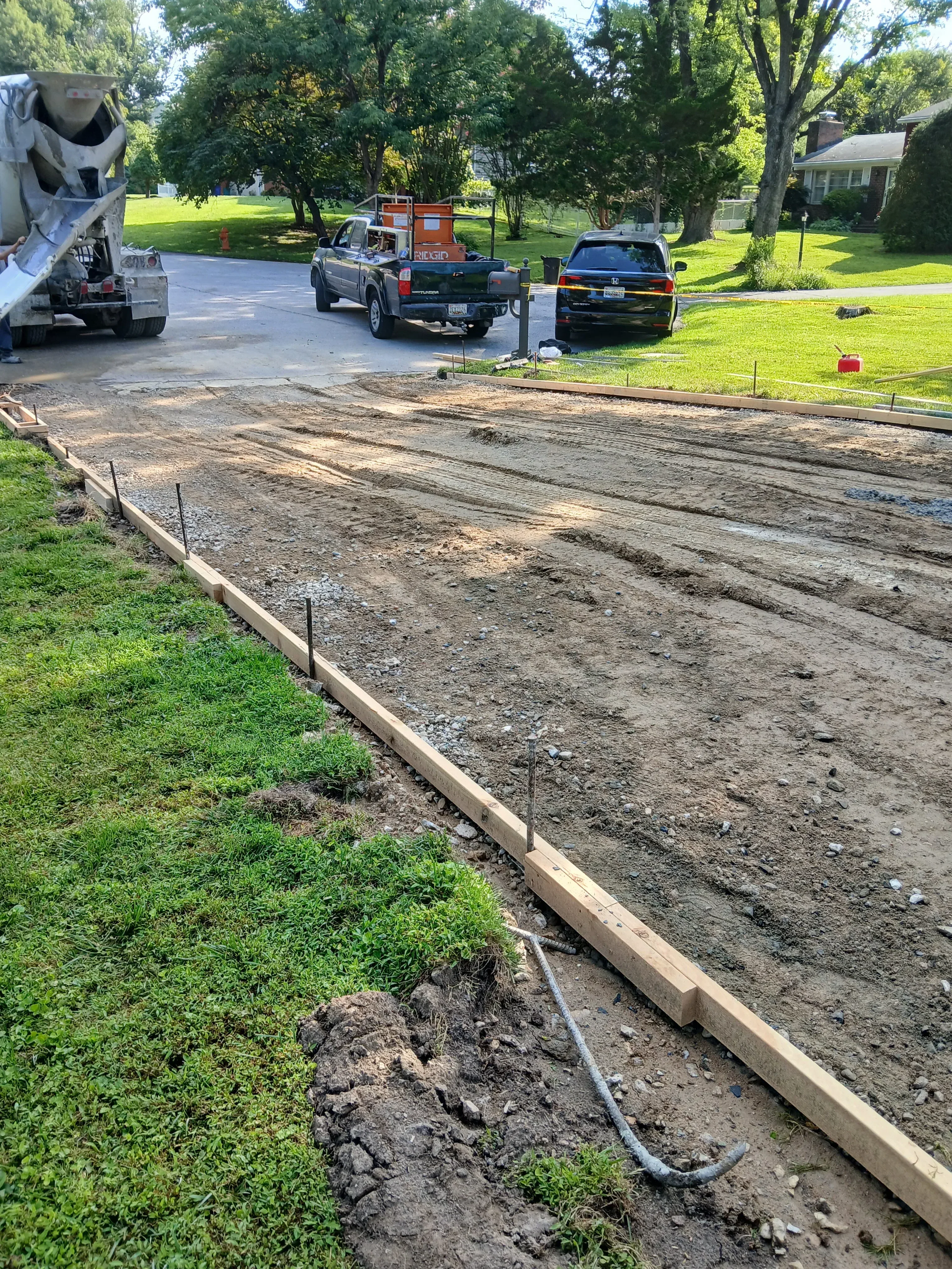 Newly paved asphalt driveway with concrete edging and metal drainage pipe installation