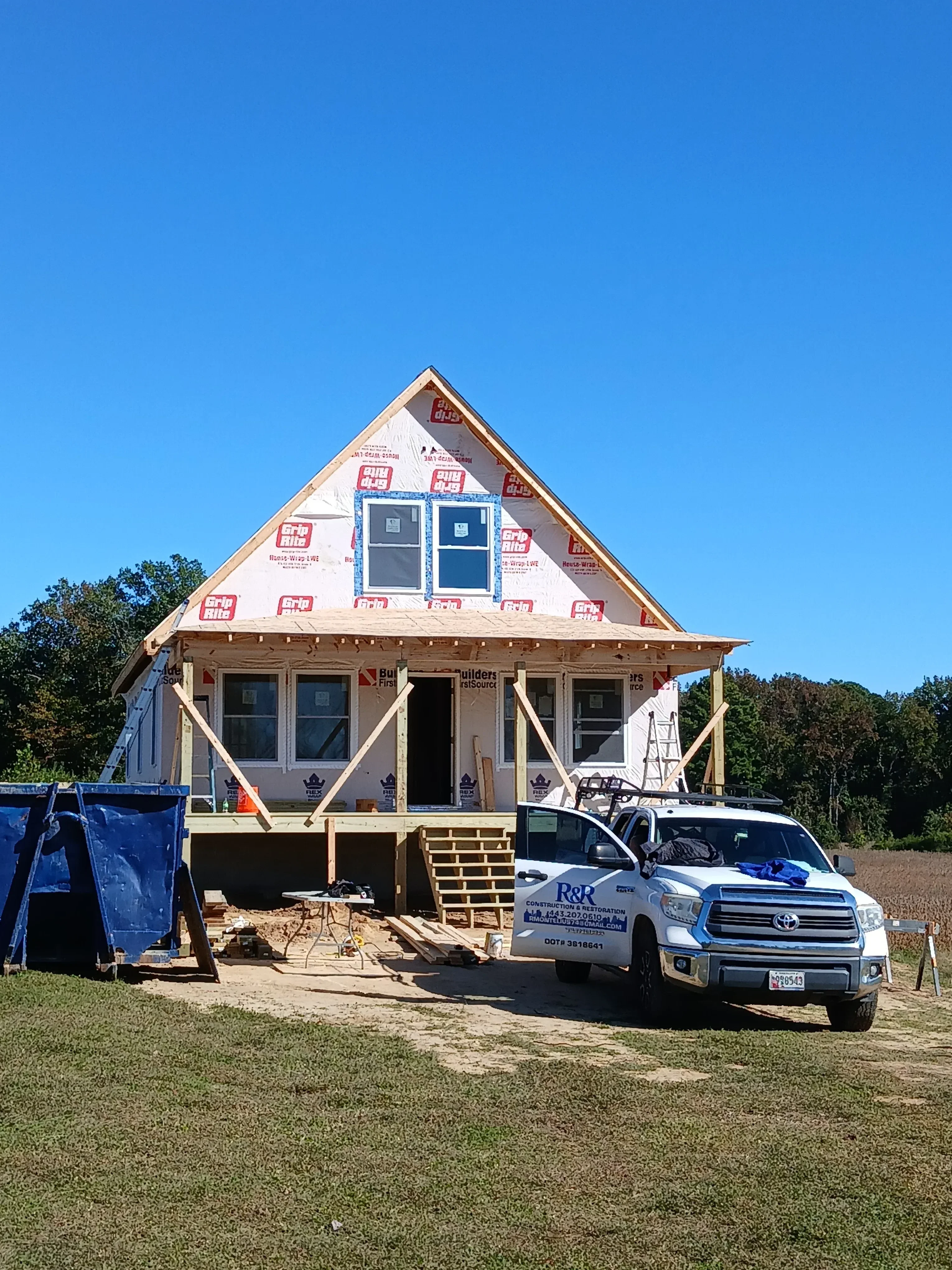 Wood-framed residential home with installed windows, house wrap, and structural framing visible
