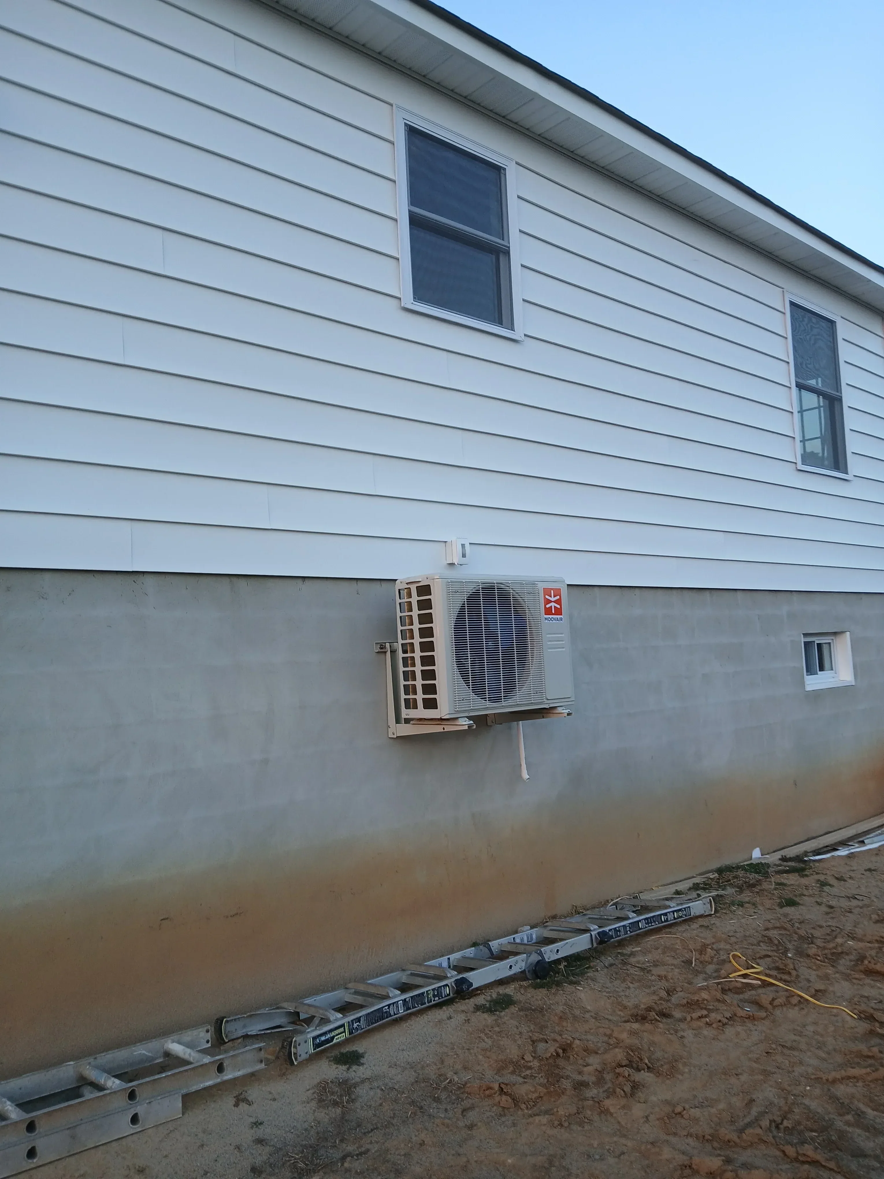 Vertical metal siding installation with windows and exterior HVAC unit mounted on building facade