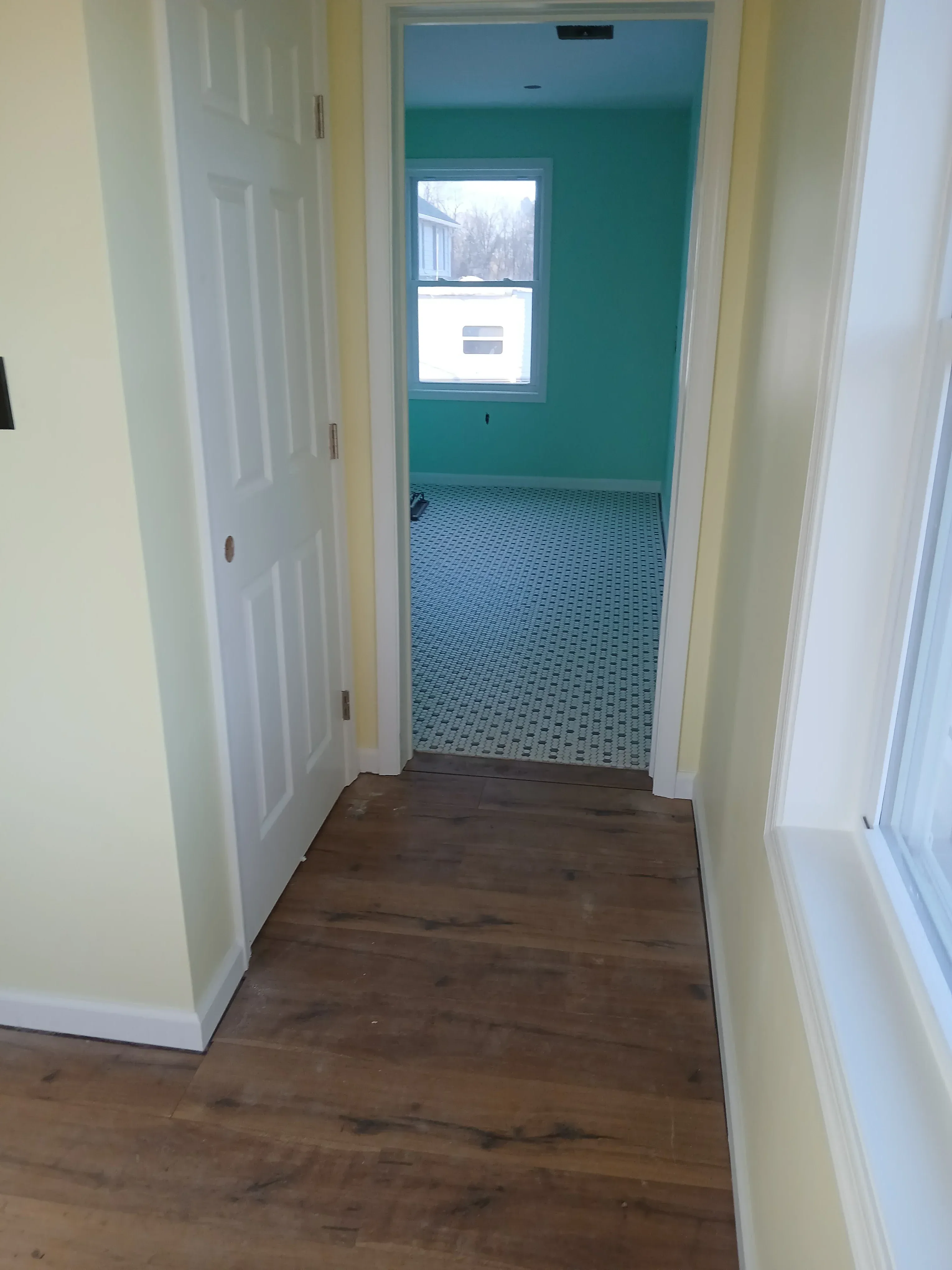 Interior renovation with painted drywall, new window, patterned tile, and wood cabinetry