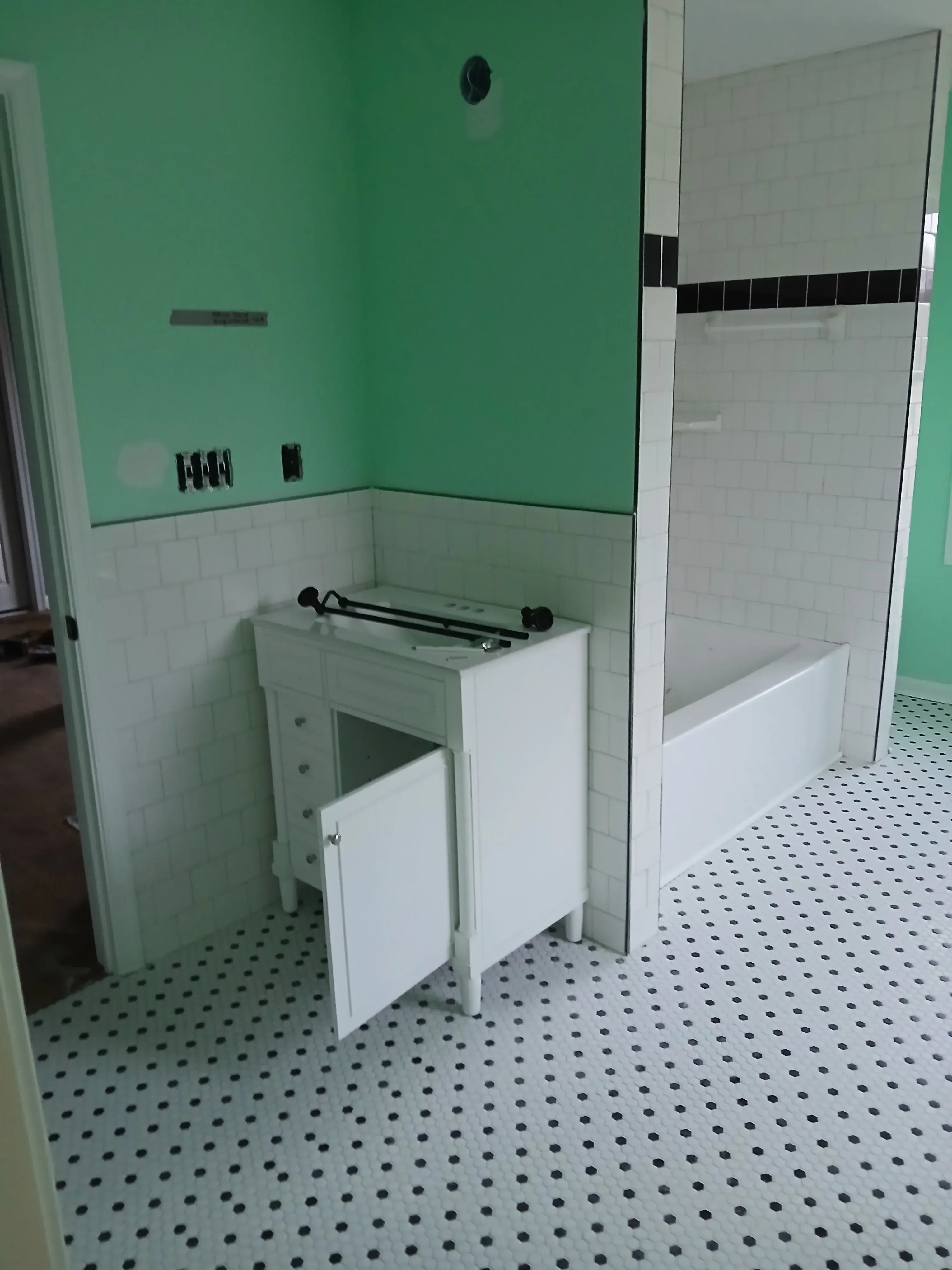 Bathroom with white cabinetry, dual vanities, subway tile walls, and green accent wall