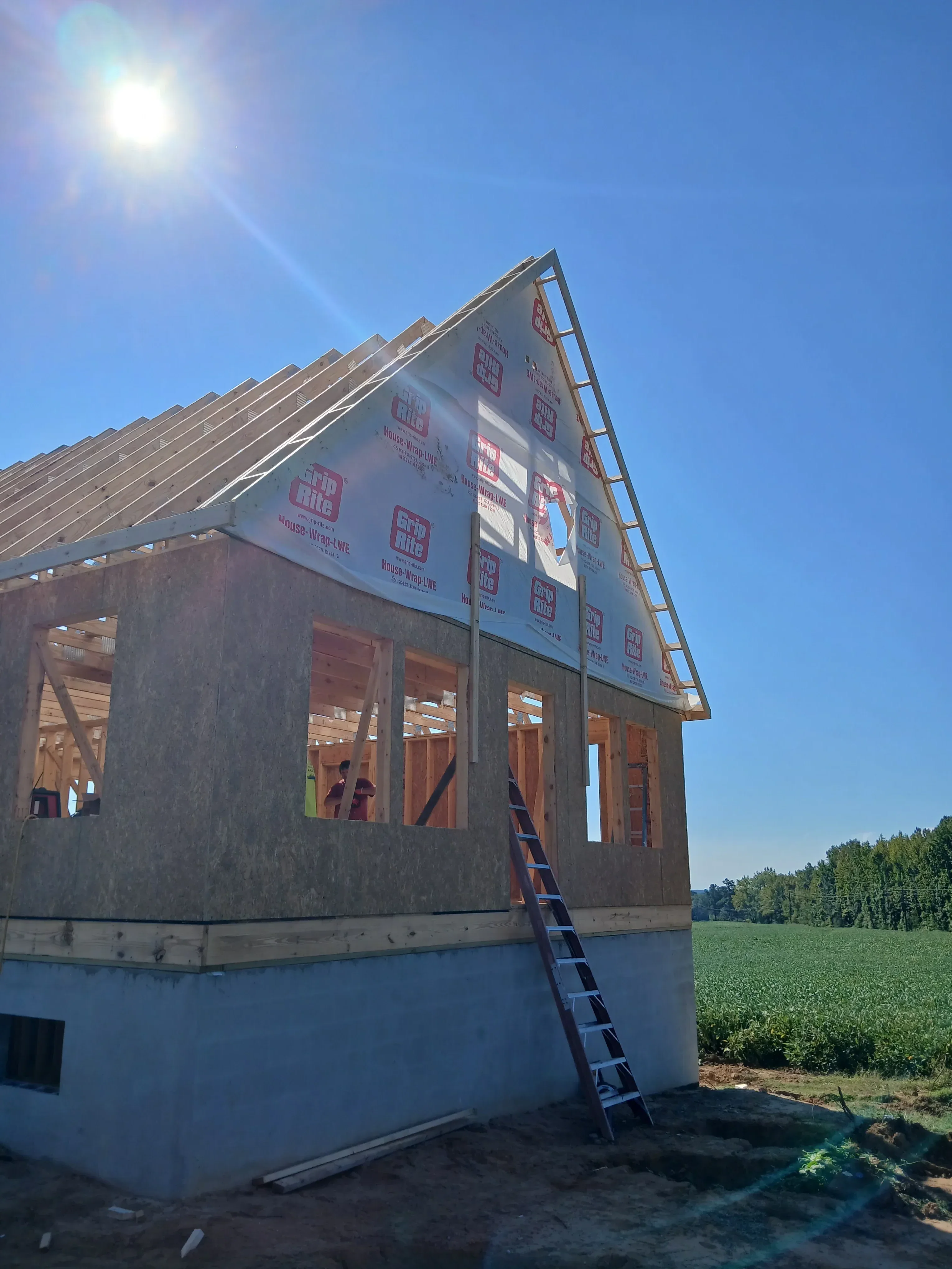 Roof framing with trusses, sheathing, and underlayment on brick residential building