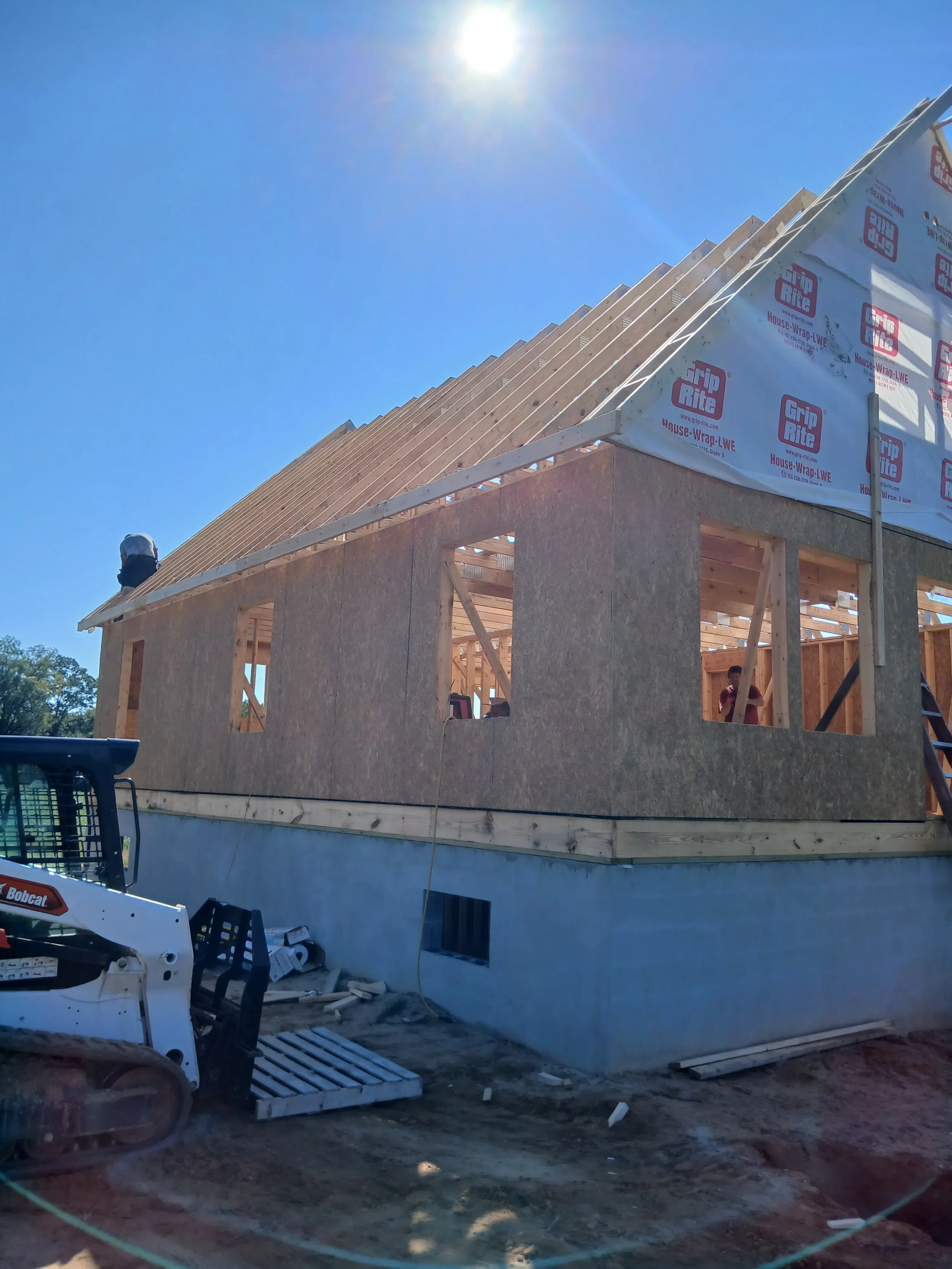 Brick residential building facade with new window frames and protective weather wrap during construction