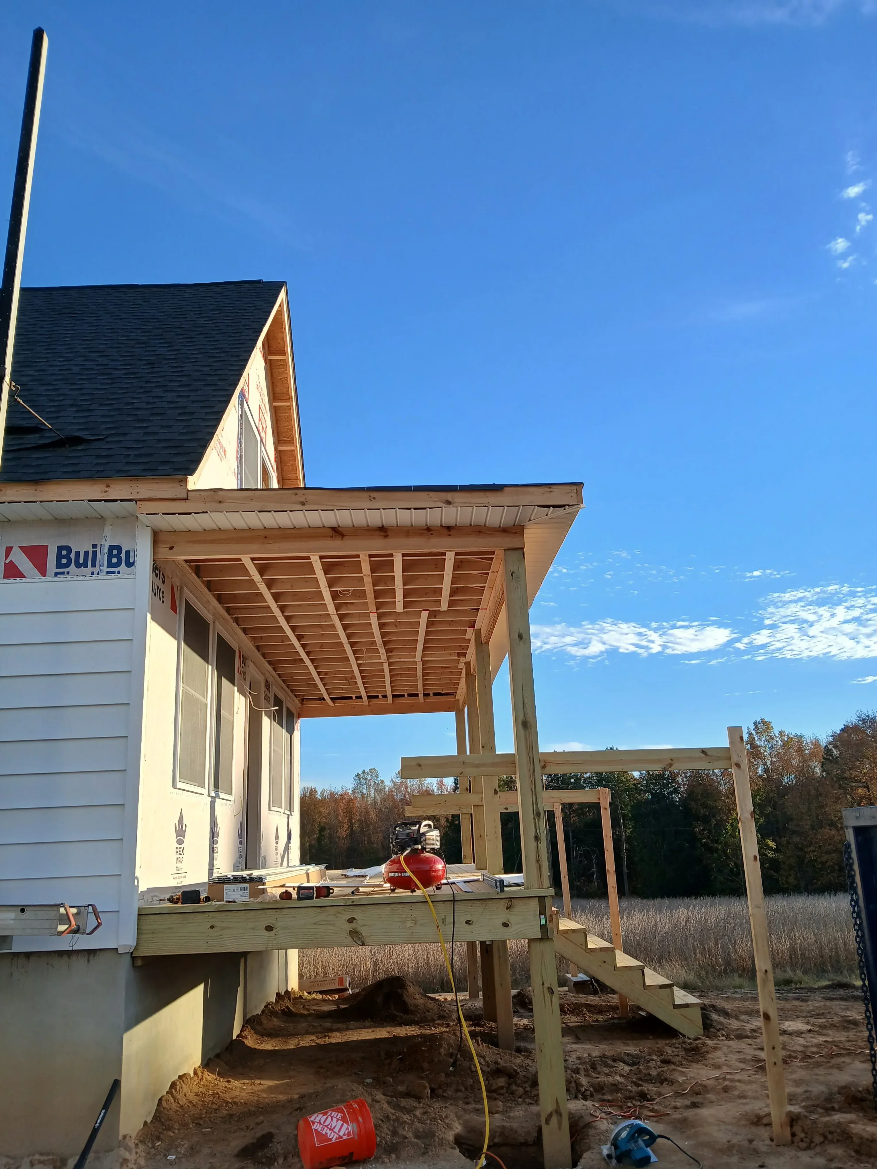 Wood deck with pergola, composite decking, and vertical slat gate against stone building
