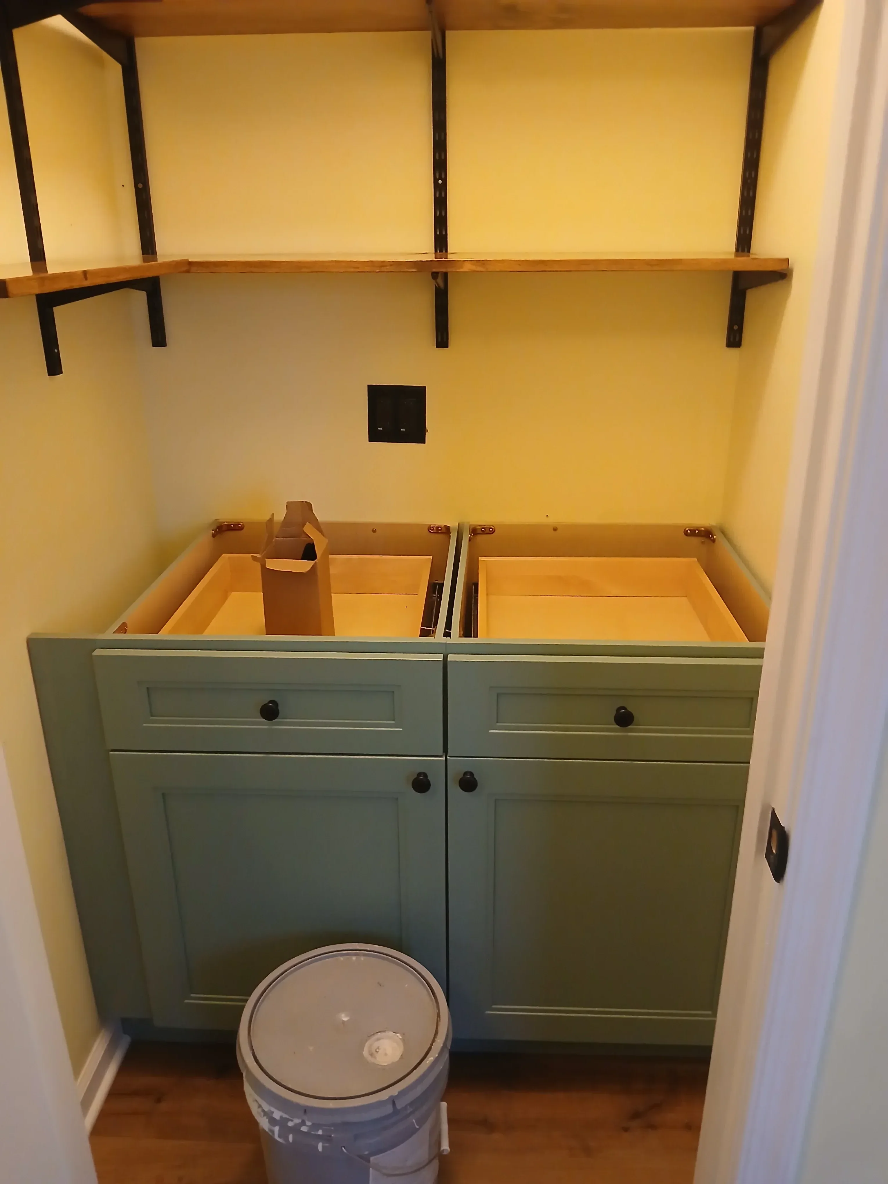 Custom painted cabinets with black hardware, yellow drywall, and sage green cabinetry in finished interior space