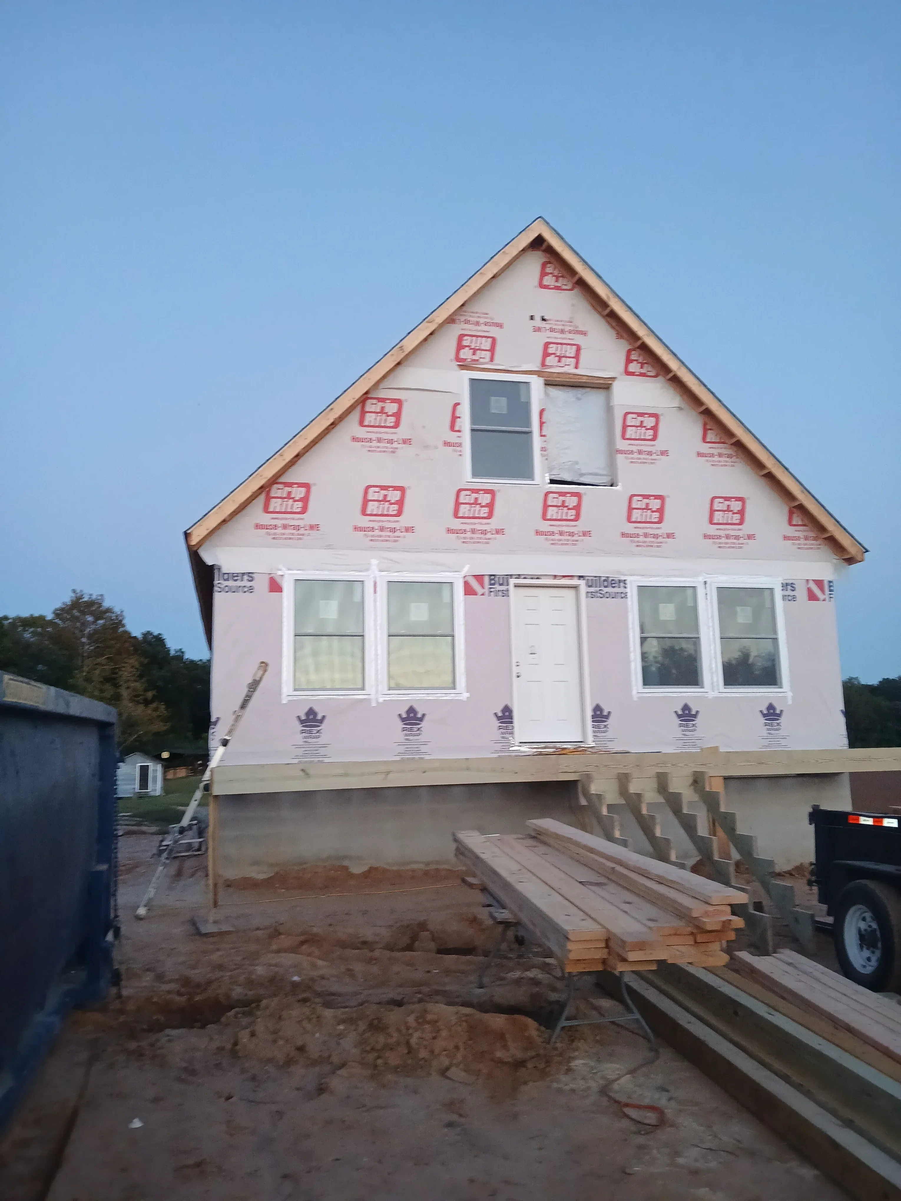 House wrap installation with vinyl windows, copper gutters, and wood framing on new construction