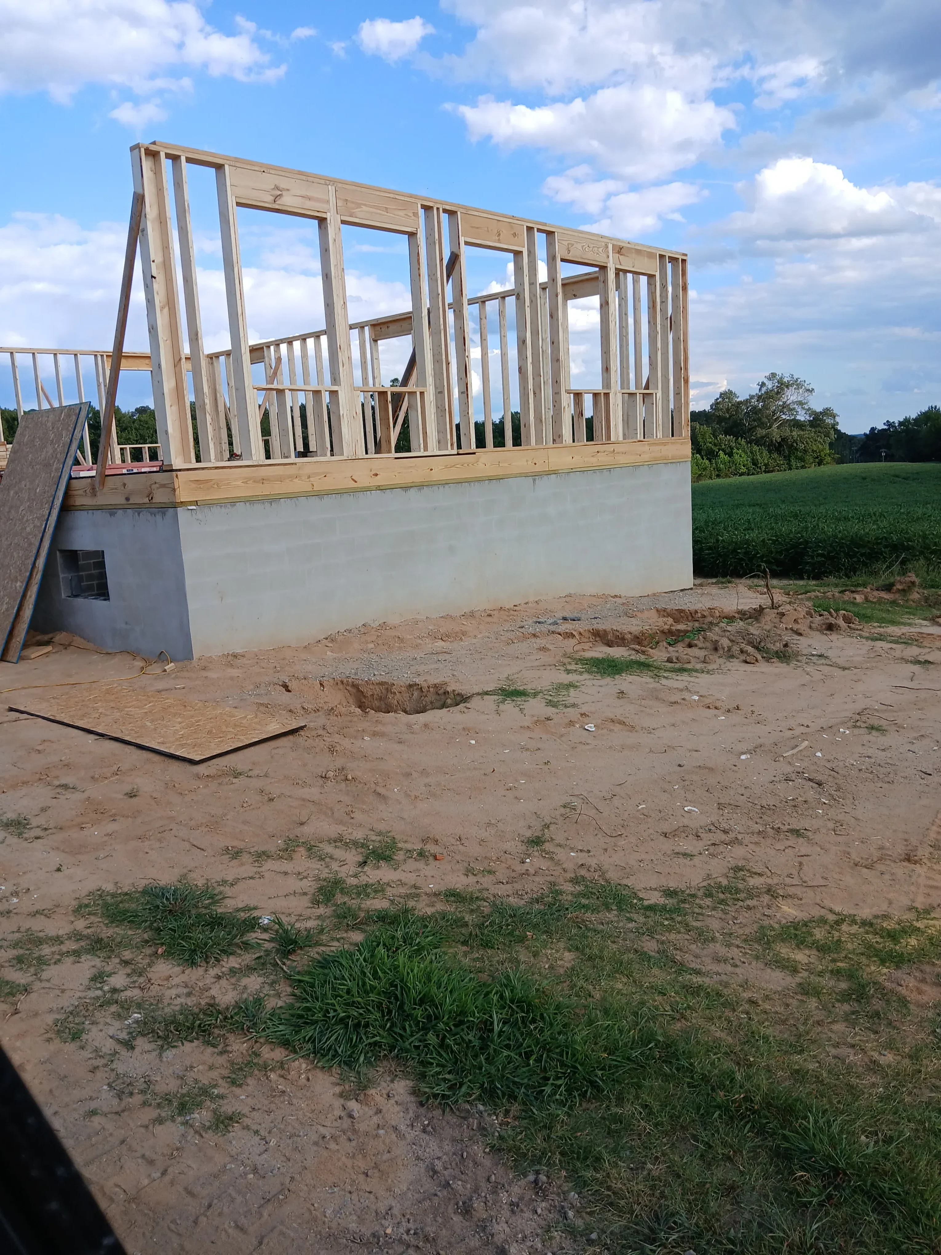 Wood-framed wall structure with concrete foundation on prepared dirt lot