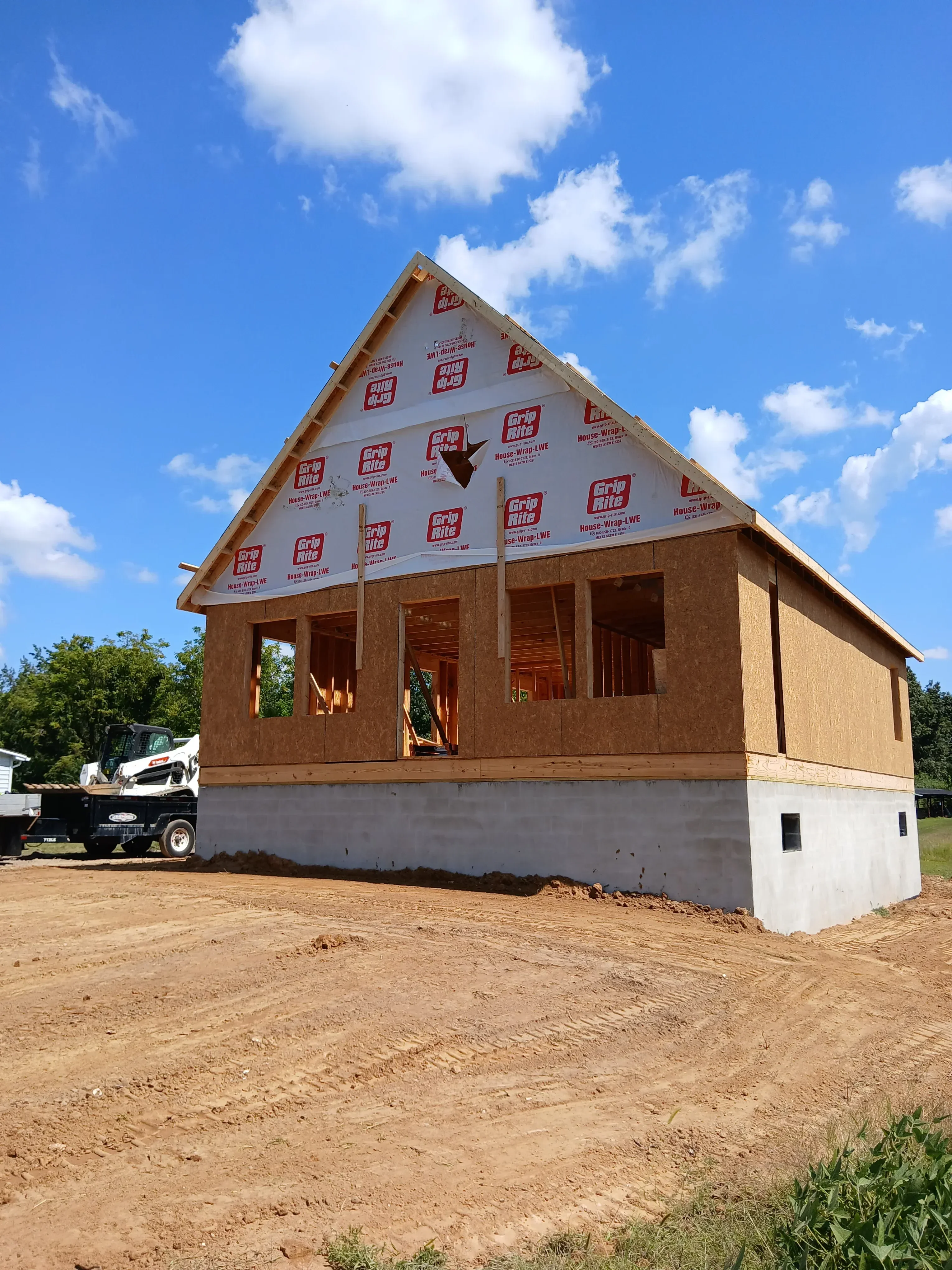Brick home under construction with weather barrier membrane and window openings