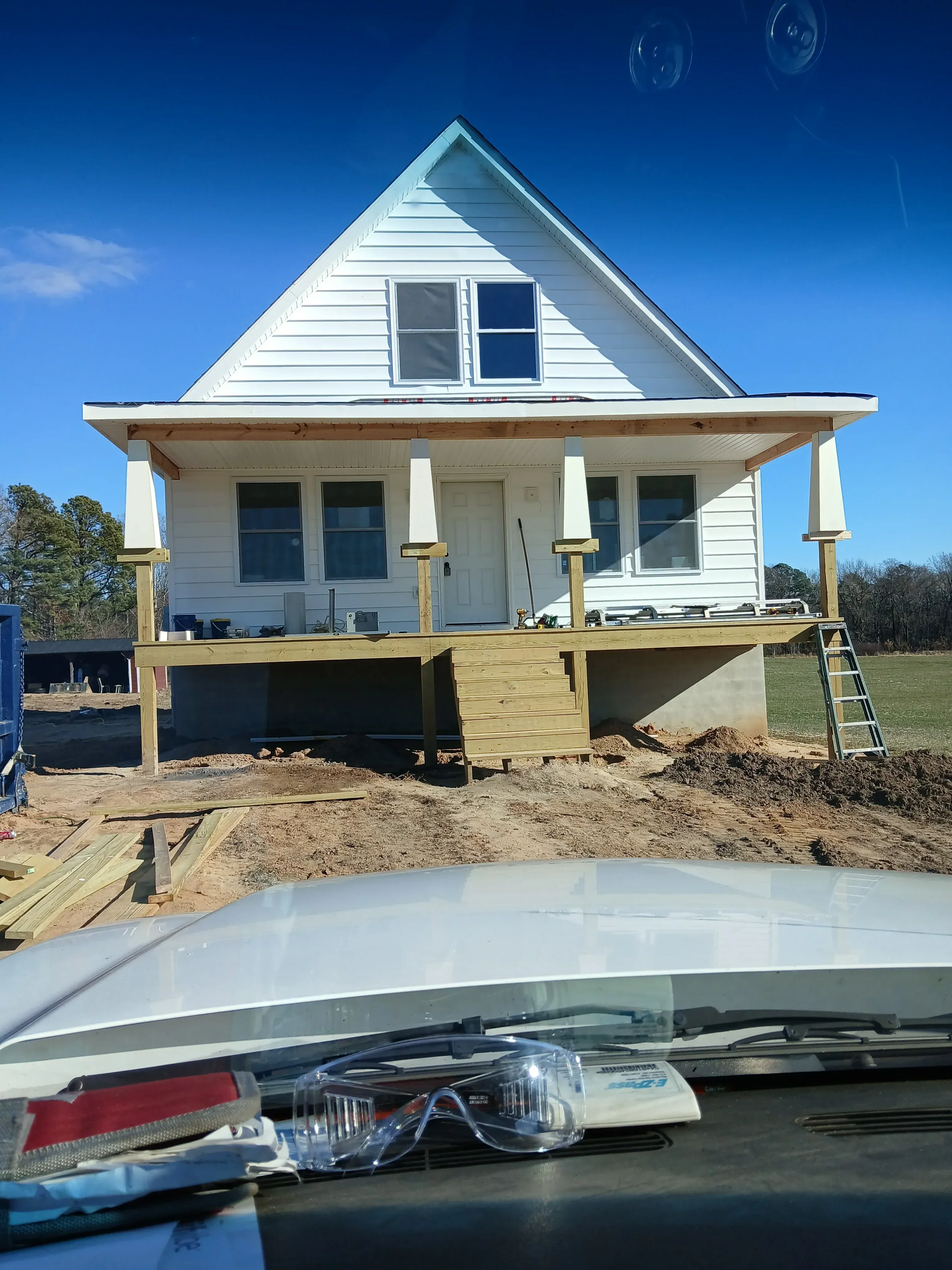 Pressure-treated wood deck with stairs, handrails, and covered entry structure under construction