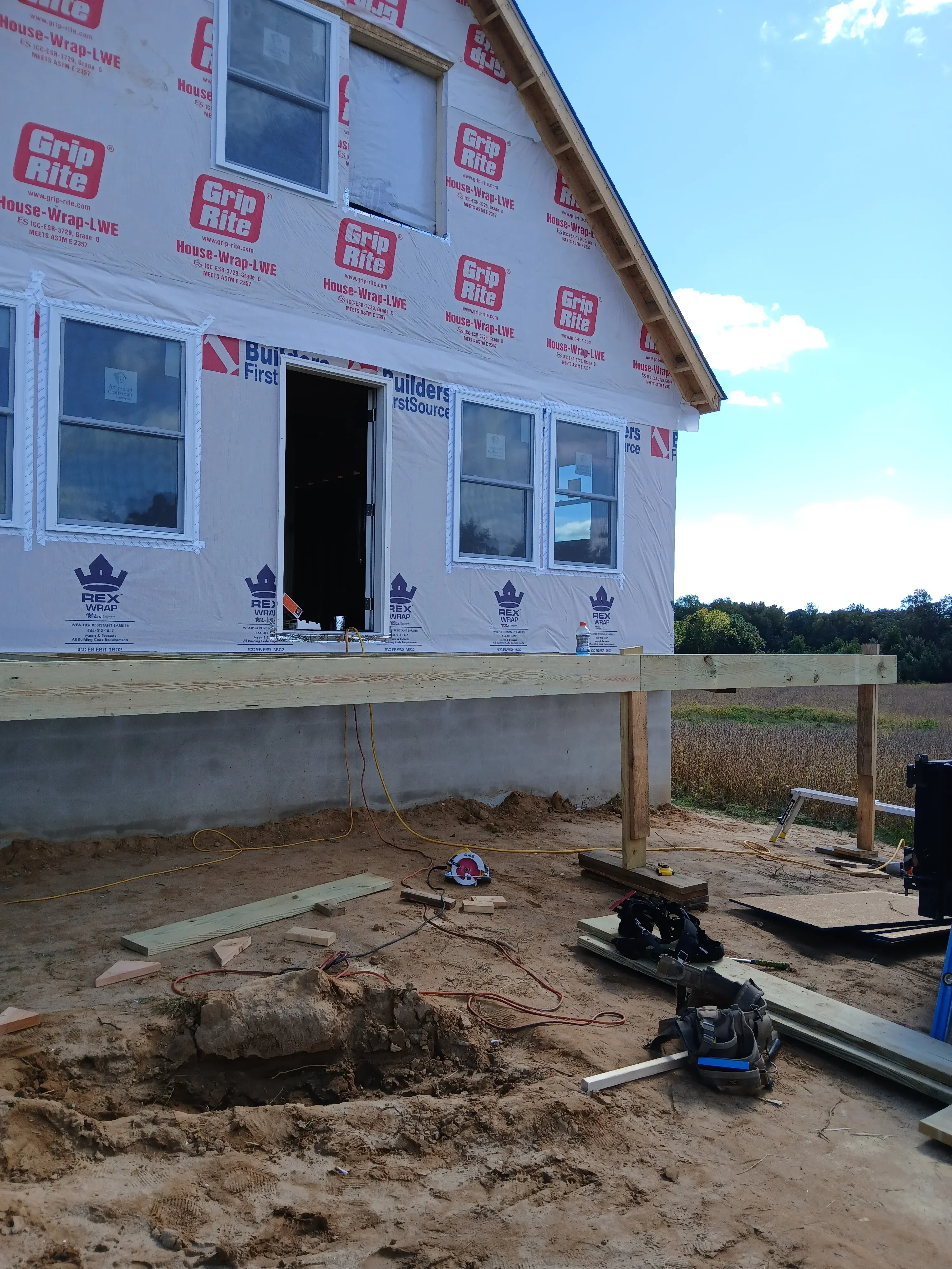 New construction framing with housewrap, treated lumber studs, and vinyl window installation