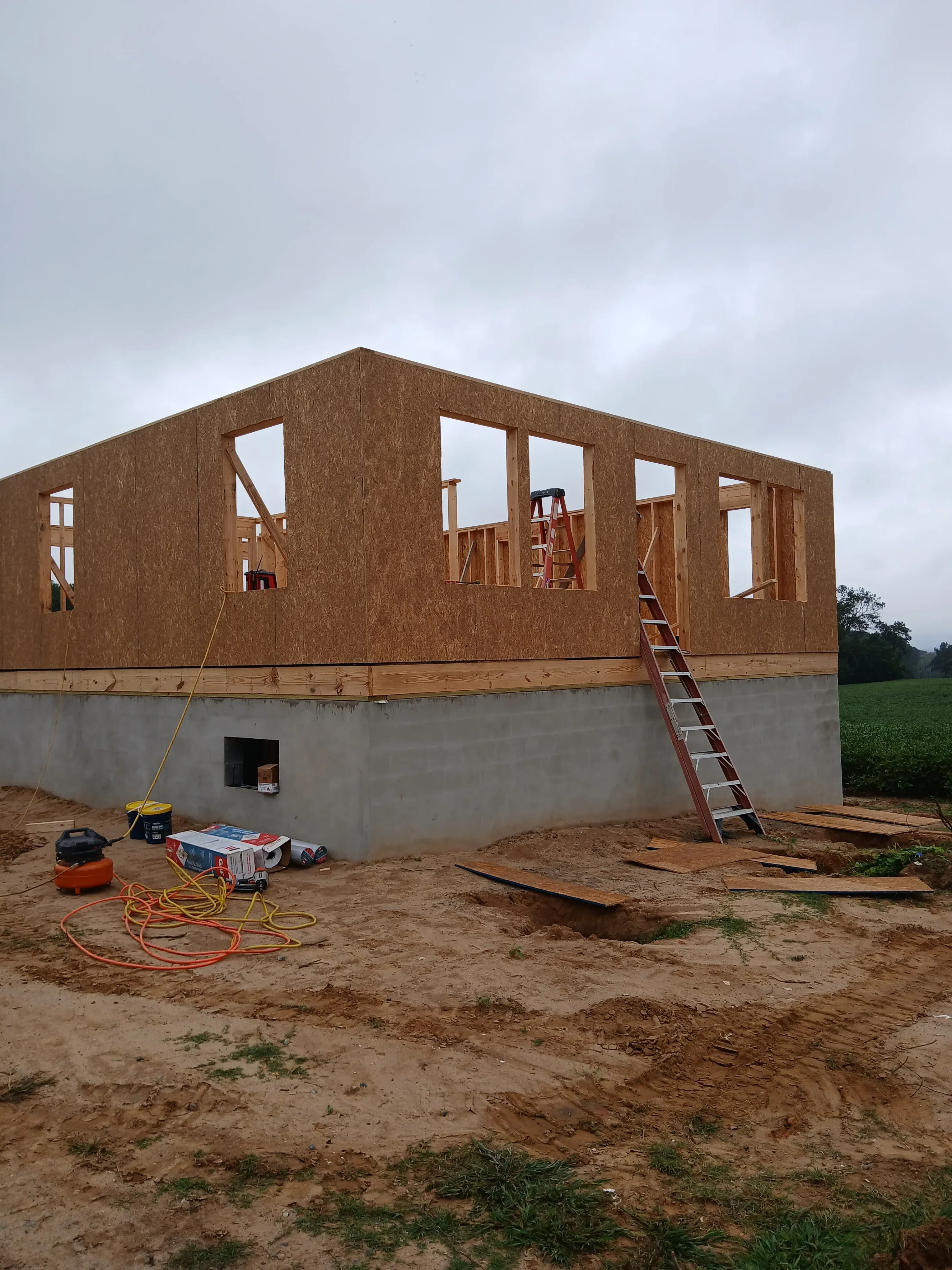 Brick masonry building with wood framing, window openings, and concrete foundation during construction phase