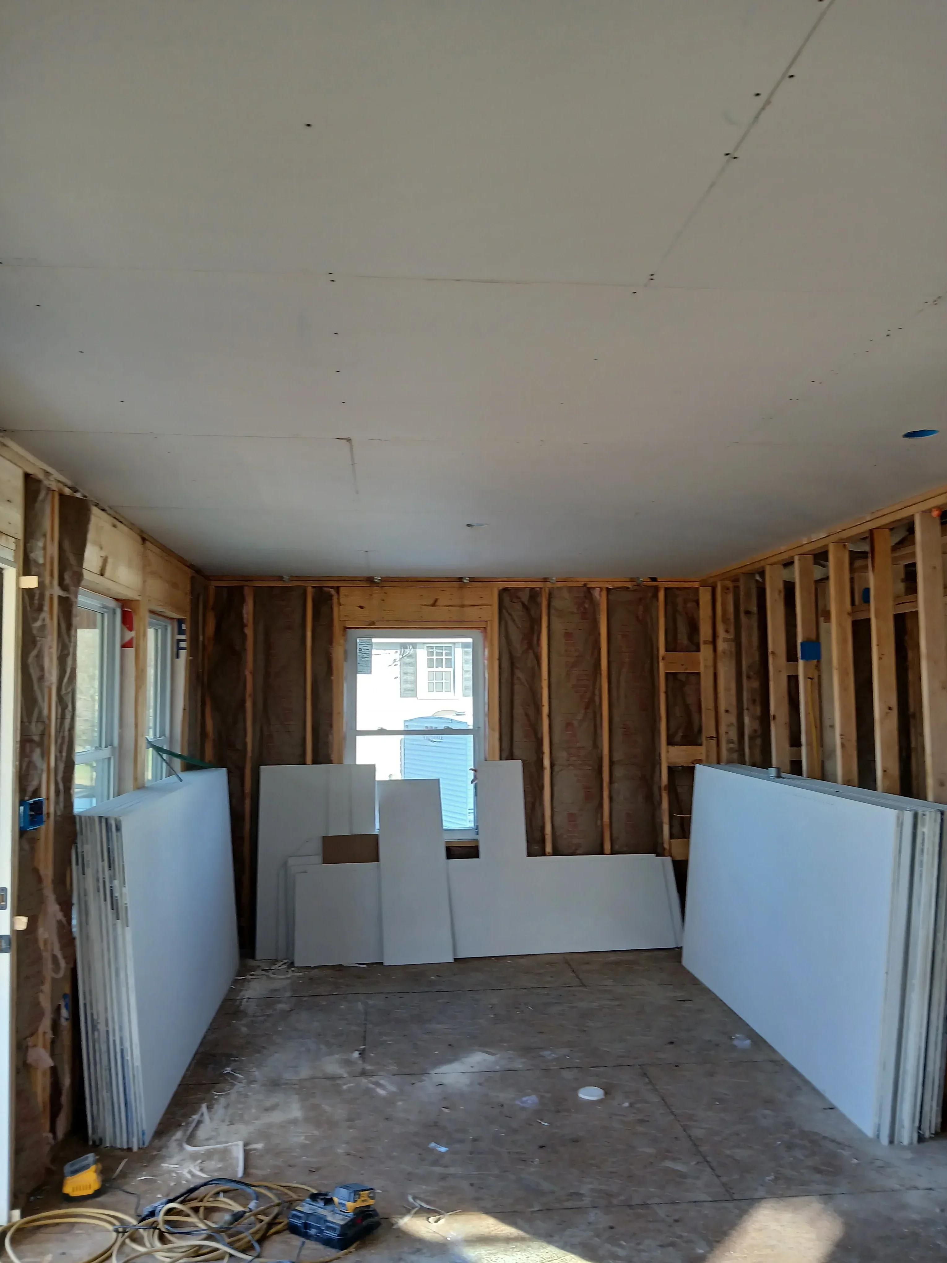 Interior framing with wooden joists, wall studs, and drywall installation in progress