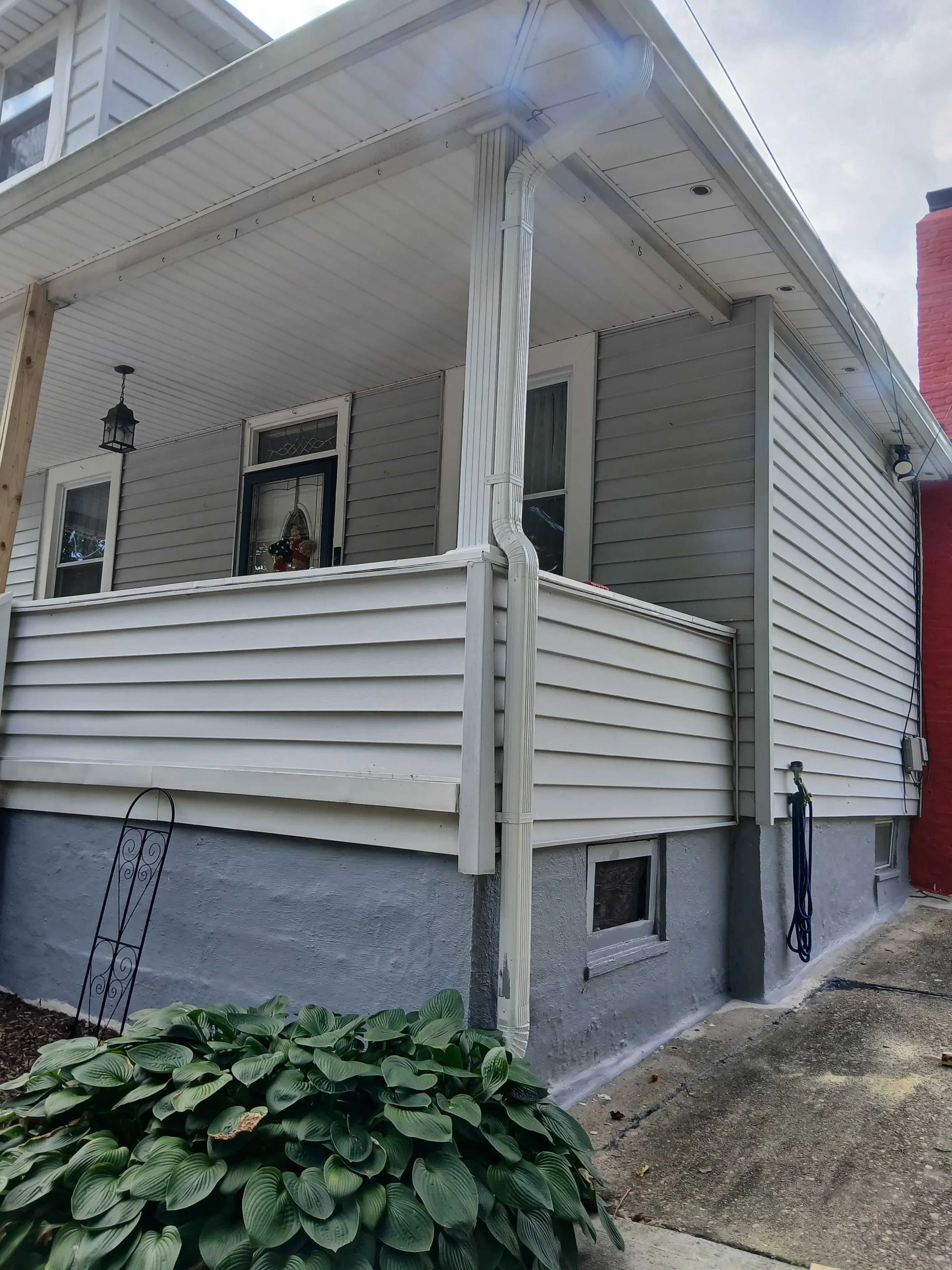 Standing seam metal roof and vertical panel siding on residential building with guttering