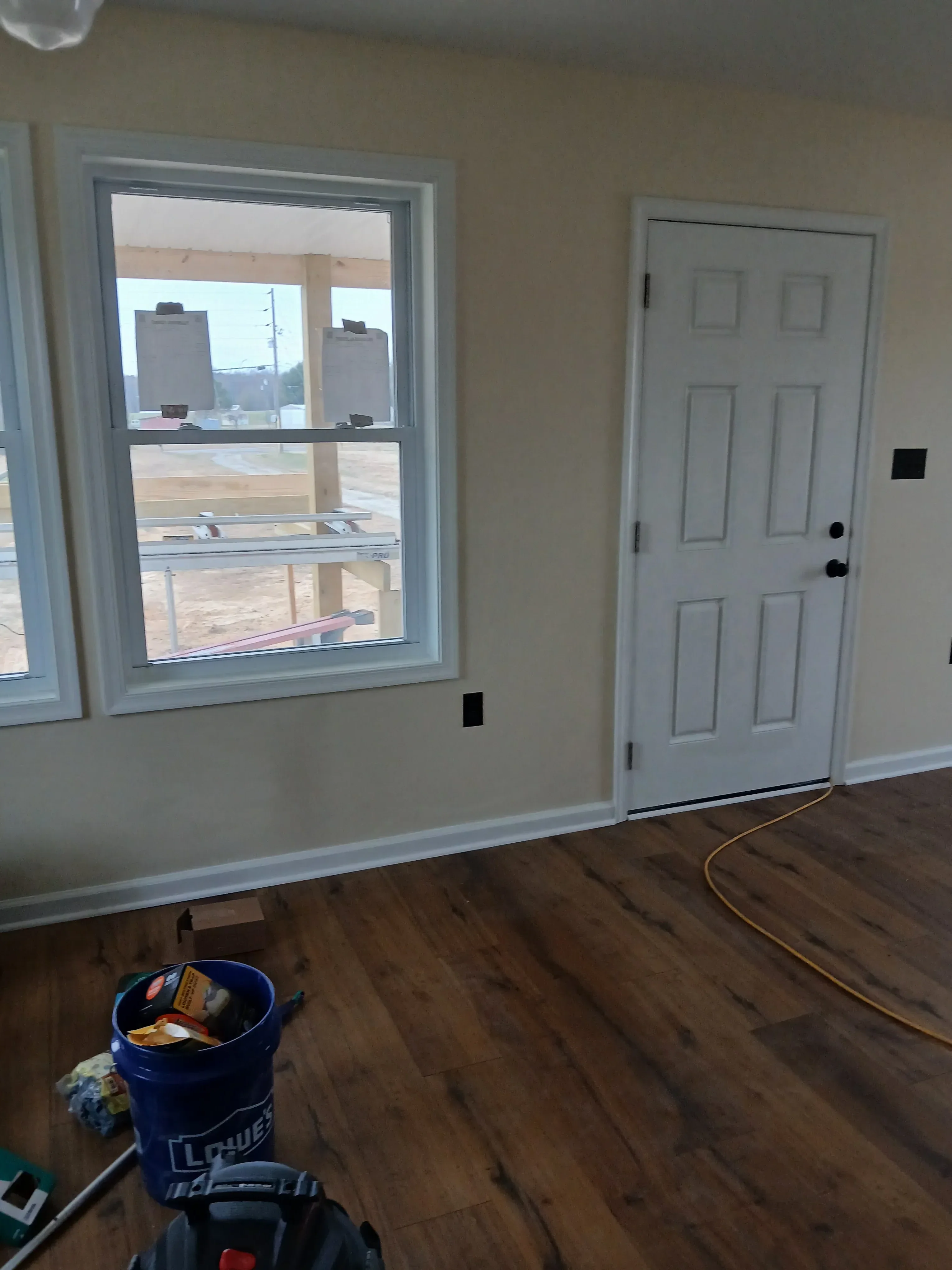 White six-panel garage door and dual-pane sliding window with aluminum frames installed in drywall opening
