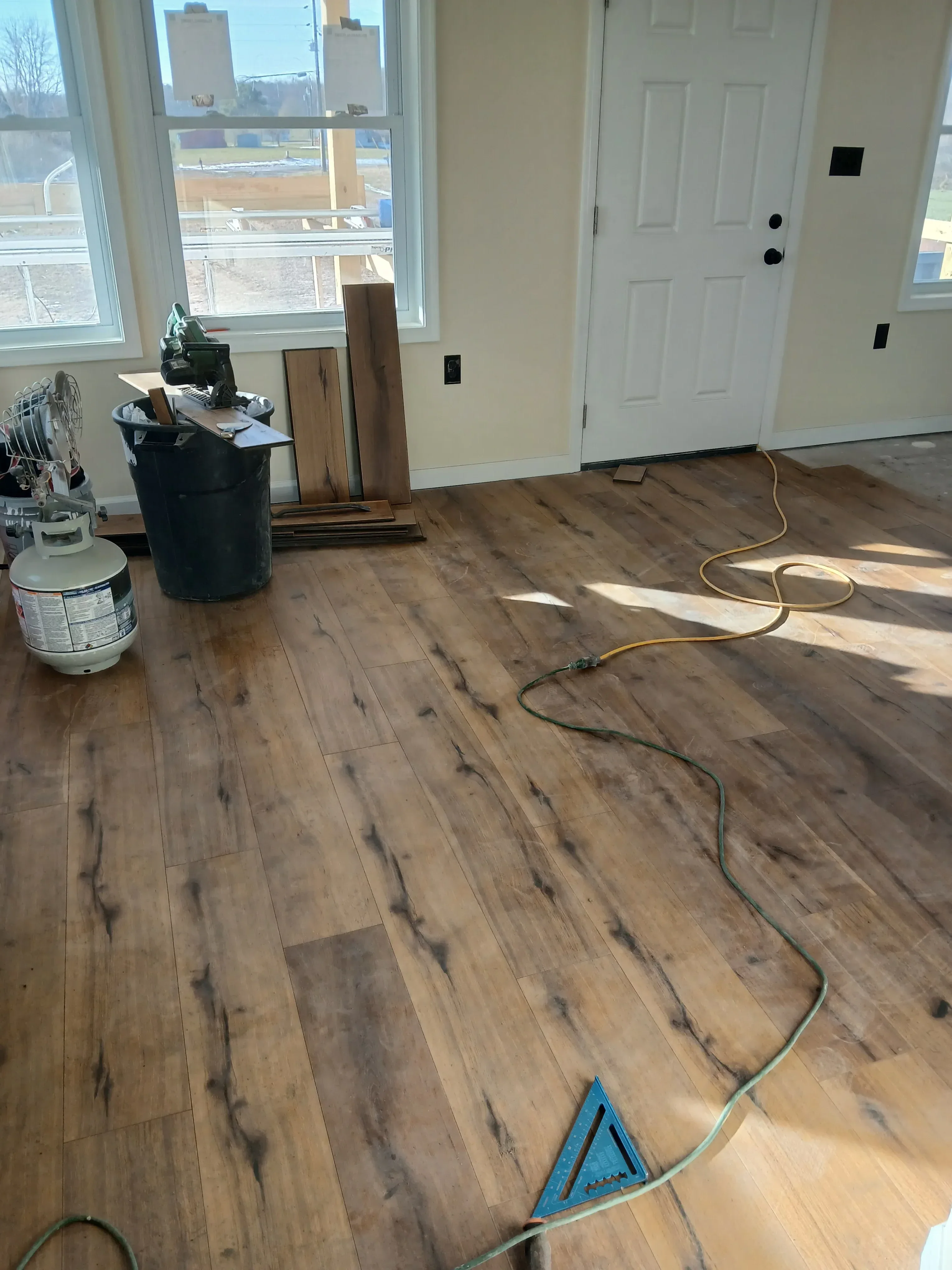 Wide-plank hardwood flooring installation with electrical wiring and drywall work visible