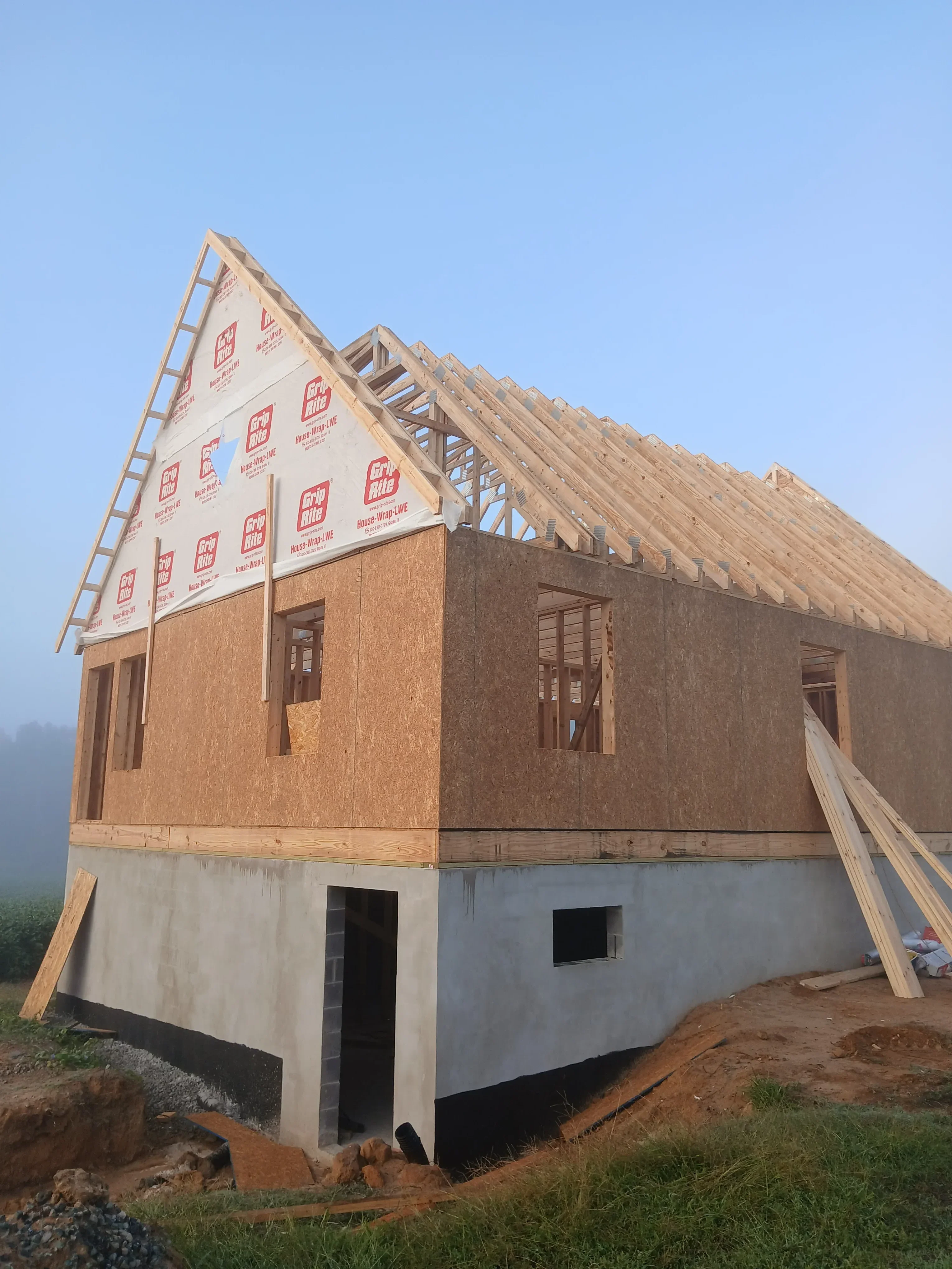 Brick home with new roof framing, OSB sheathing, and weather barrier installation in progress