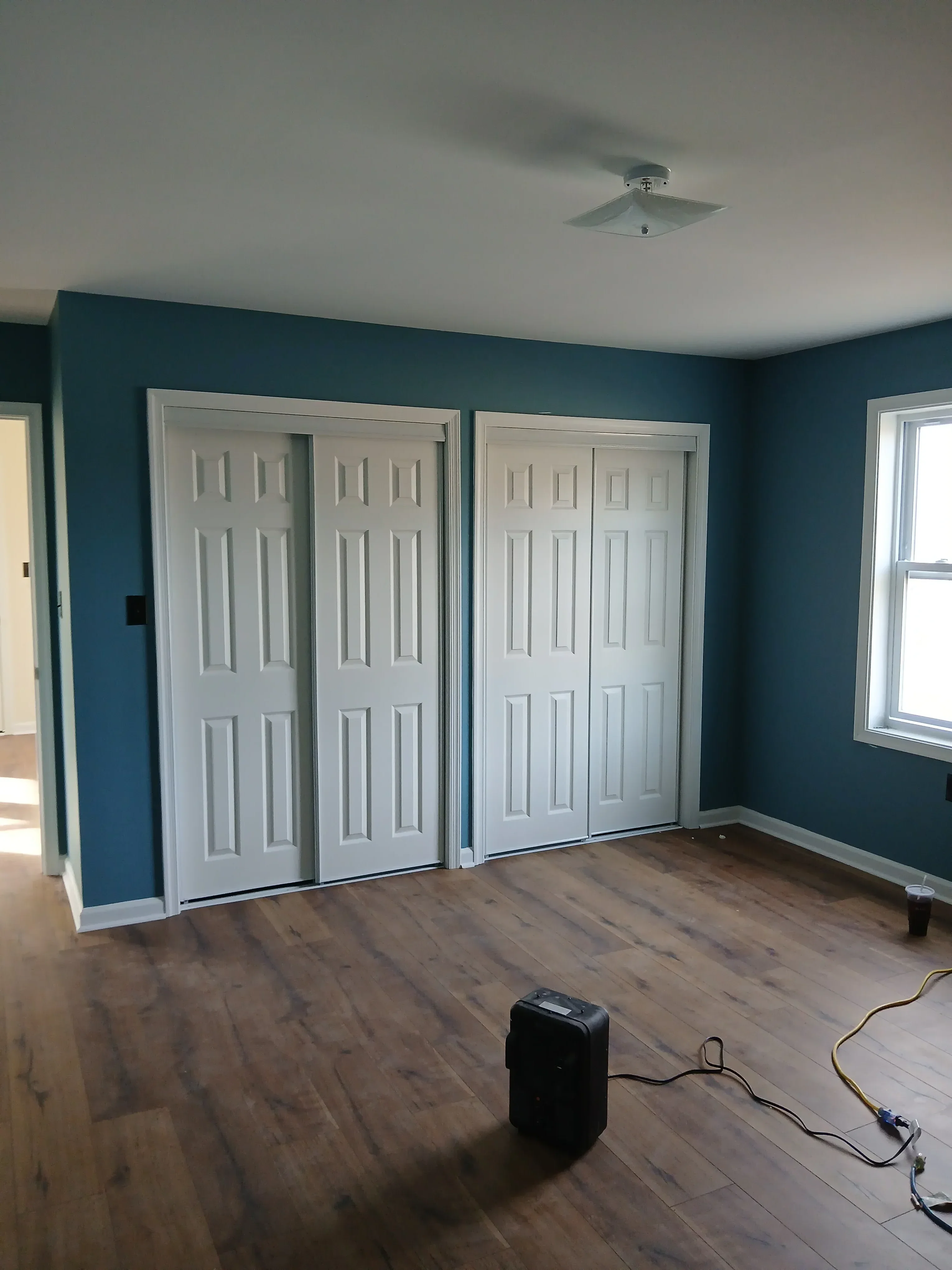 Three white raised-panel garage doors installed with aluminum frames in teal garage