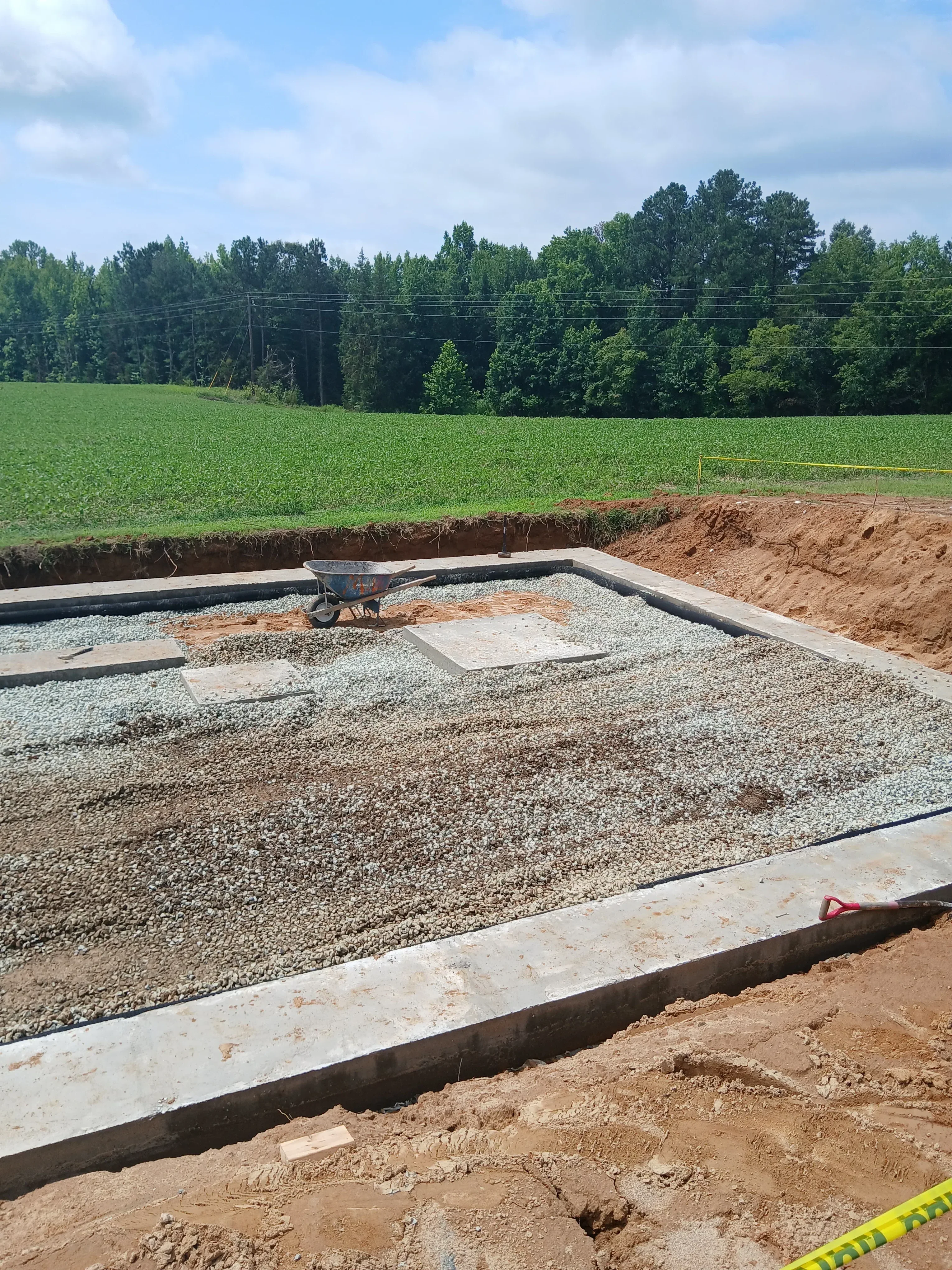 Driveway base preparation with gravel, landscape fabric edging, and compacted subgrade