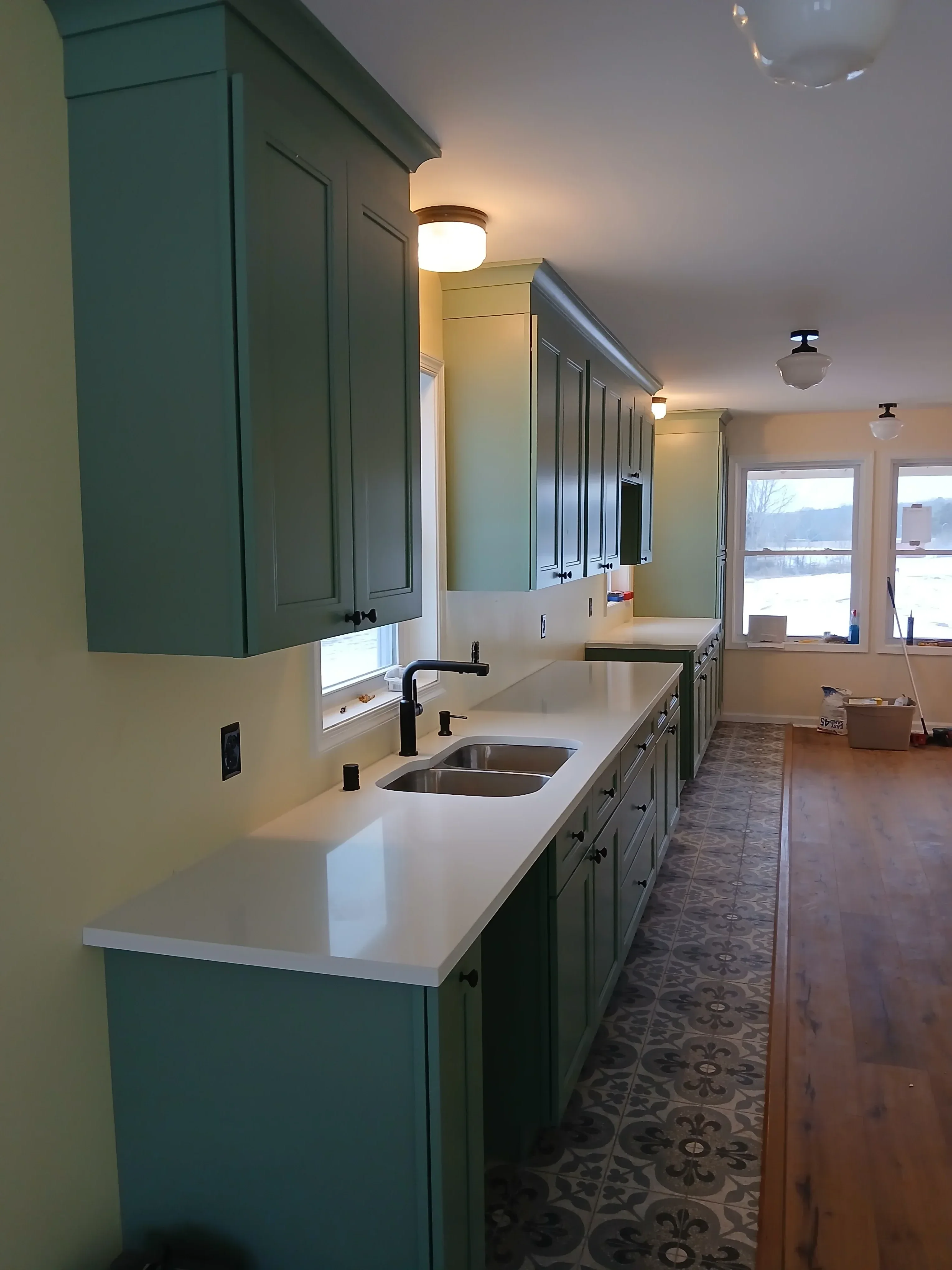 Laundry room with sage green and white cabinetry, tile backsplash, and recessed lighting