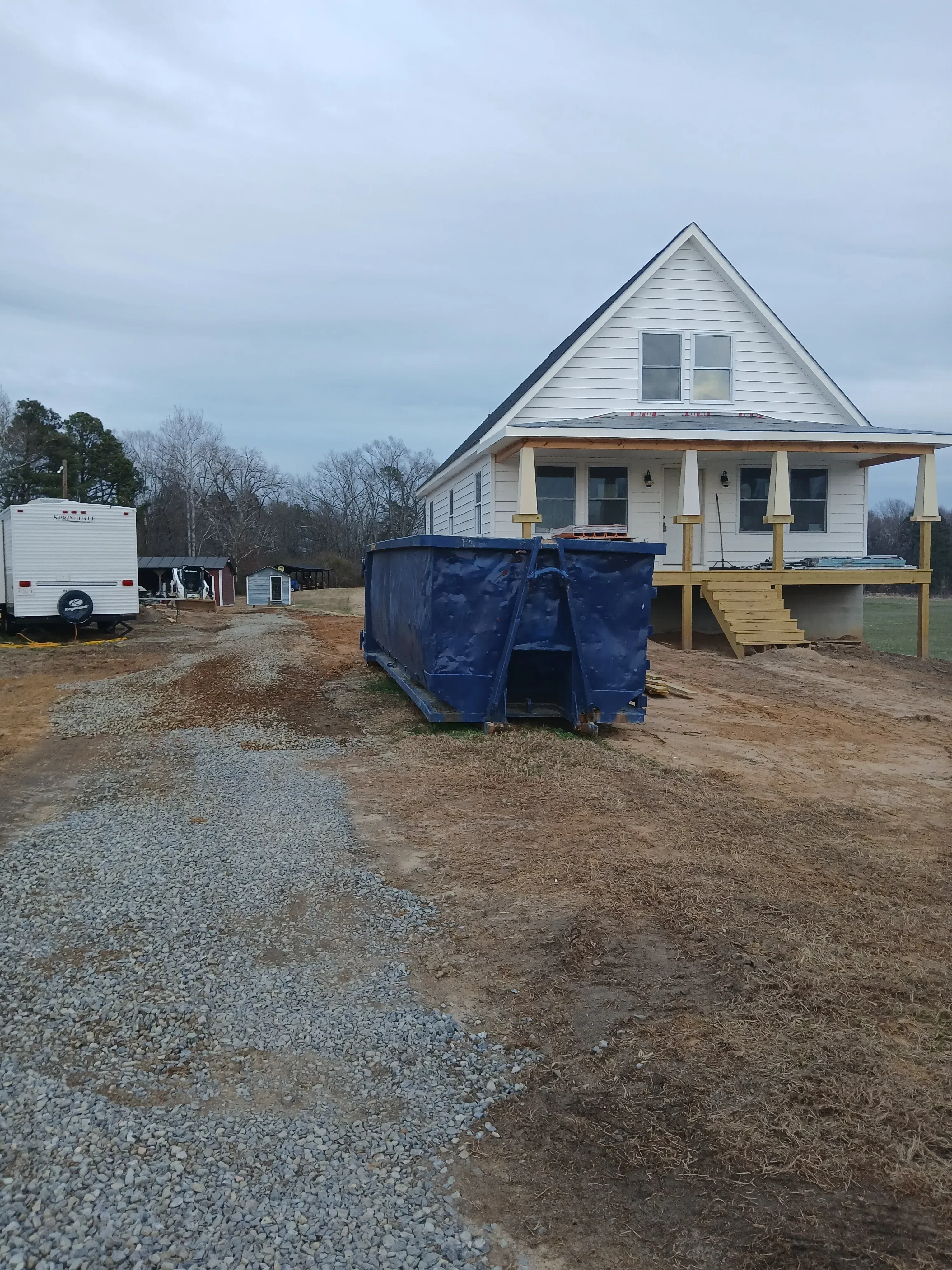 Wood-framed residential construction with metal roofing, structural beams, and multi-level framing in progress