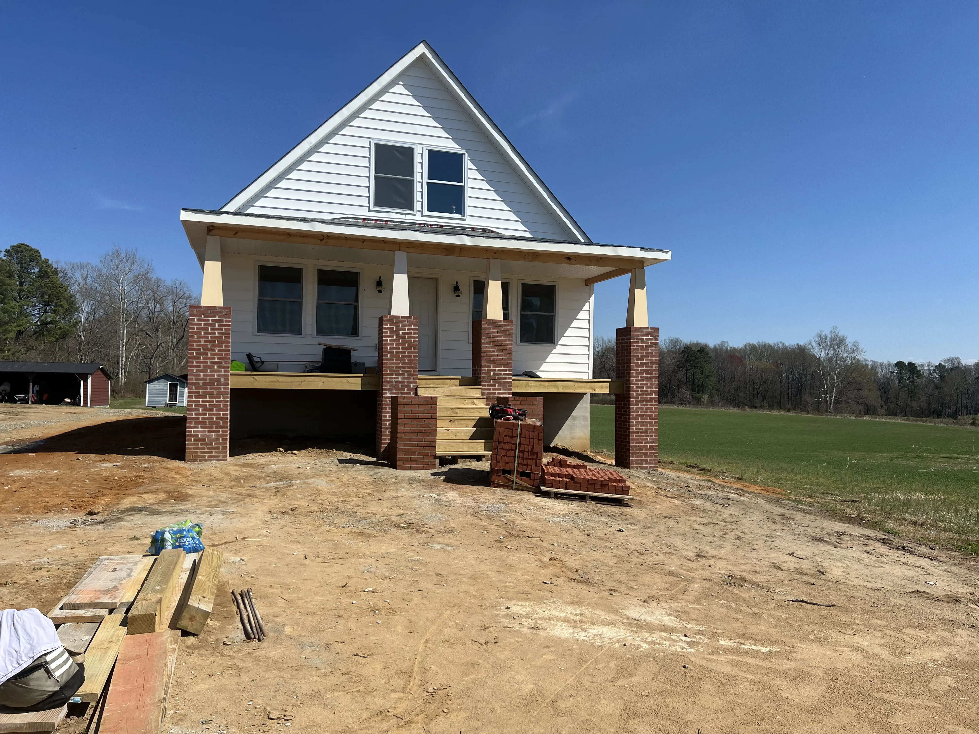 Raised foundation home with brick piers, vinyl siding, and wood porch framing under construction
