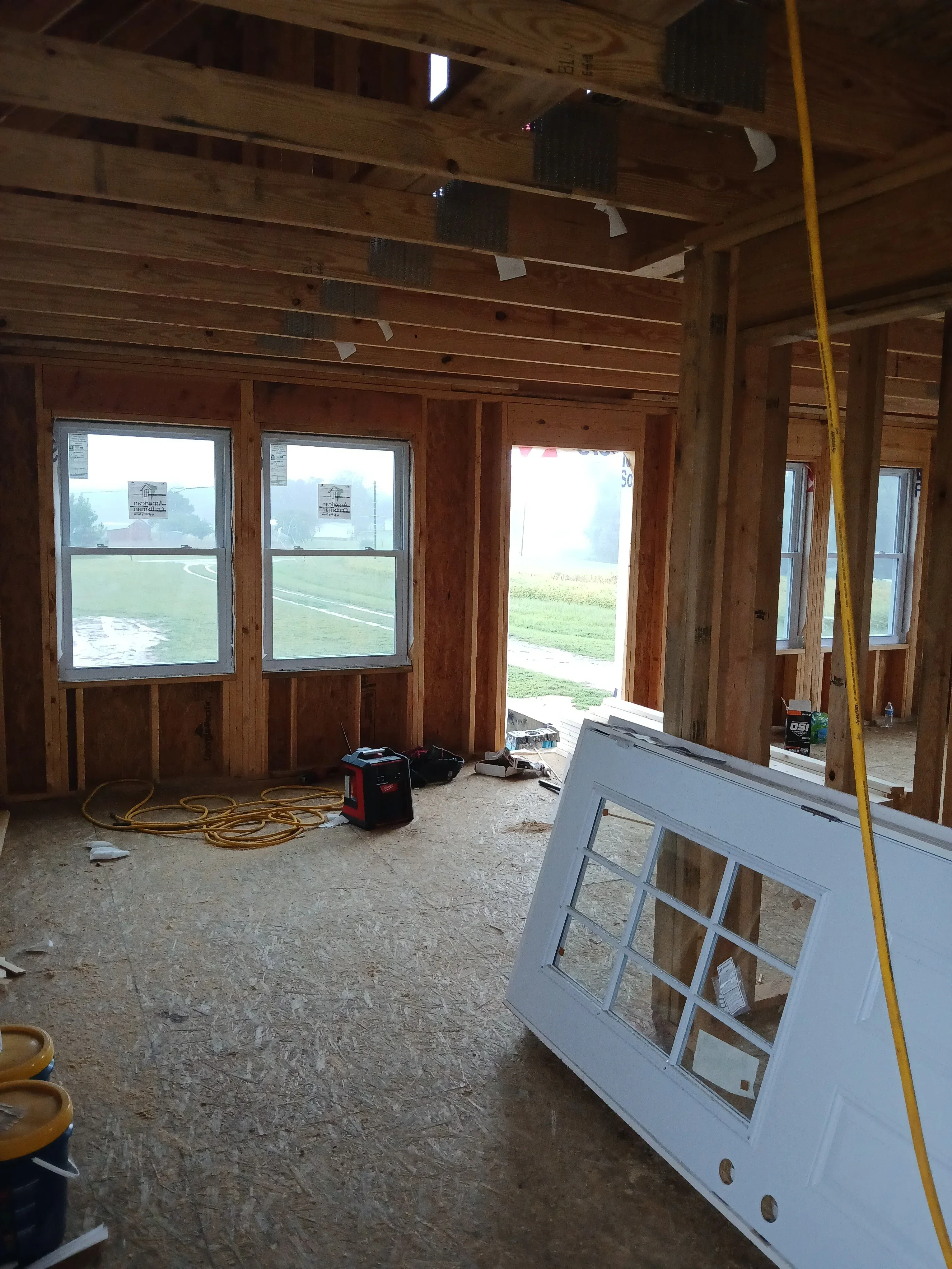 Log cabin interior with exposed timber beams, horizontal log walls, and installed double-hung windows